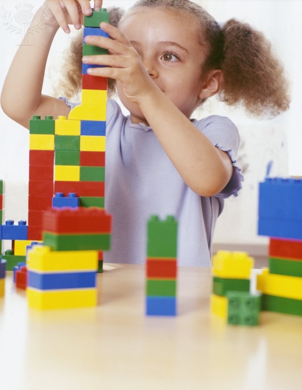 Girl playing with lego, building a colorful tower. 